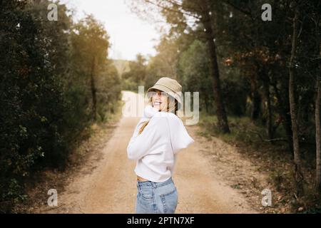 Bella ragazza dai capelli biondi posa in mezzo a un campo di fiori di colza gialli fiorenti Foto Stock