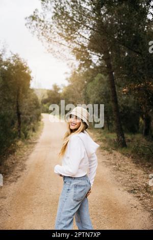 Bella ragazza dai capelli biondi posa in mezzo a un campo di fiori di colza gialli fiorenti Foto Stock