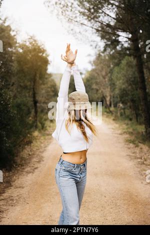 Bella ragazza dai capelli biondi posa in mezzo a un campo di fiori di colza gialli fiorenti Foto Stock