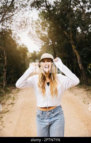 Bella ragazza dai capelli biondi posa in mezzo a un campo di fiori di colza gialli fiorenti Foto Stock