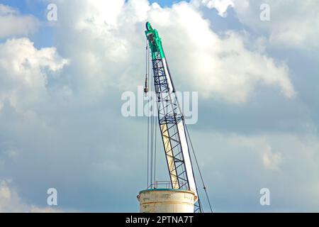 Gru ascensore verde funzionante nel cielo blu backgound Foto Stock