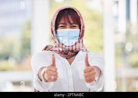 Donna d'affari, covid e pollici in su per la conformità del posto di lavoro, politica di salute del virus corona e musulmano nella maschera di faccia. Ritratto islamico dei dipendenti con ok, l Foto Stock