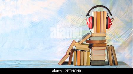concetto di audiolibri con stack di libri e cuffie rosse vintage su sfondo blu, buon spazio di copia. Foto Stock