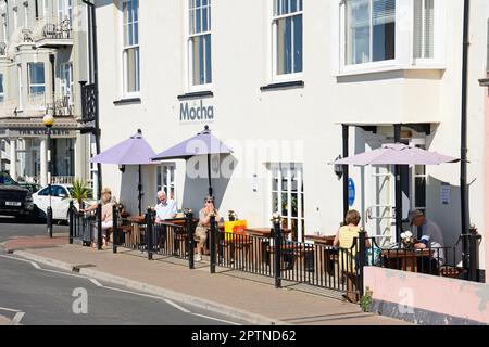 I turisti si rilassano in una caffetteria sul marciapiede lungo la passeggiata, Sidmouth, Devon, Regno Unito, Europa. Foto Stock