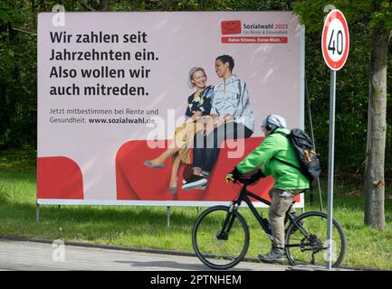 Un grande poster che chiede le elezioni sociali del 2023 il 31 maggio 2023 è su una strada trafficata, un ciclista sta guidando davanti ad esso. Si svolge ogni sei anni per tutti i prestatori di pensione, di assicurazione sanitaria e di assicurazione contro gli infortuni. Oberhausen, 27 aprile 2023 Foto Stock