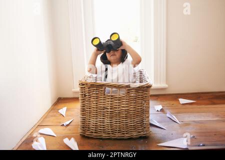 Lascia che la tua immaginazione prenda il volo. Un ragazzino che gioca con aeroplani di carta mentre si siede in un cestino Foto Stock