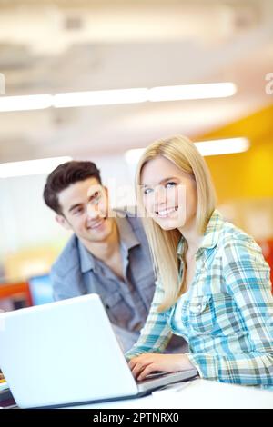 Fare i compiti a casa su un notebook. Due studenti sorridenti che si aiutano a vicenda con i compiti a casa. Foto Stock