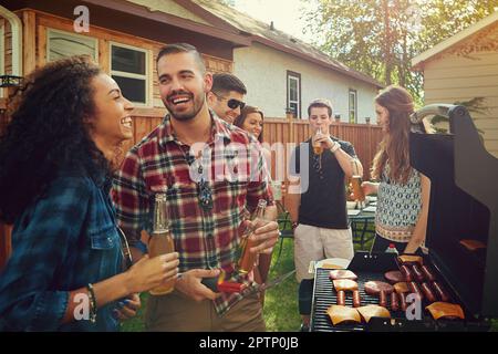 È bello mangiare... un gruppo di amici che hanno un barbecue all'aperto. Foto Stock