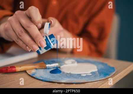 Primo piano delle mani femminili su una tavolozza di vernice acrilica blu. Concetto di vacanza e hobby. Foto Stock