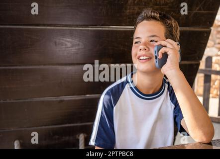 ragazzo di 12 anni che usa lo smartphone all'aperto. Foto Stock