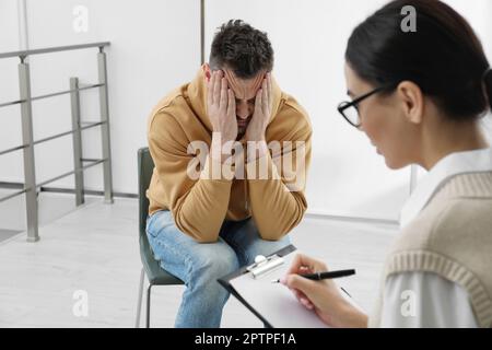 Psicoterapeuta che lavora con l'uomo tossicodipendente al chiuso Foto Stock