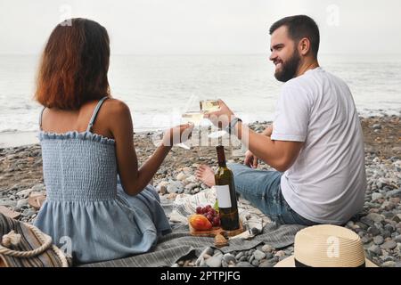 Felice giovane coppia che ha pic-nic sulla spiaggia vicino al mare Foto Stock