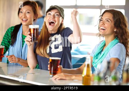 Che gioco epico. Tre amiche che si tirano indietro con qualche drink al bar e guardano lo sport Foto Stock