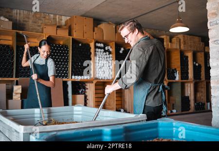 Vinicoltori che lavorano nel processo di produzione del vino con uno strumento per la stampa del vino o attrezzature in un magazzino, in un'azienda vinicola o in una distilleria. Donna, uomo o gente del vintner Foto Stock