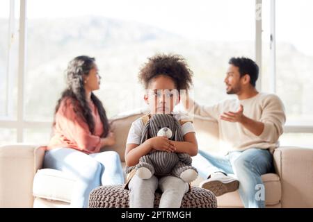 Una bambina sconvolta che stringe il suo orsacchiotto mentre guarda triste e depresso mentre i suoi genitori discutono in background. Pensare ai suoi genitori br Foto Stock