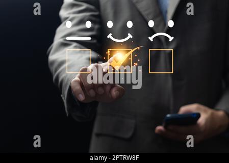 Valutazione del servizio clienti migliore eccellente valutazione aziendale concetto di esperienza. sorridendo un uomo con uno smartphone e premendo emoticon viso sorridere in sati Foto Stock