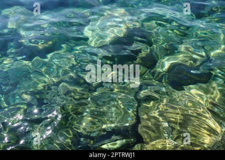 Verde azzurro turchese blu trasparente acqua salata. Vista dall'alto della superficie dell'acqua e delle increspature. Acqua mare onde sfondo. Il fondo roccioso Foto Stock