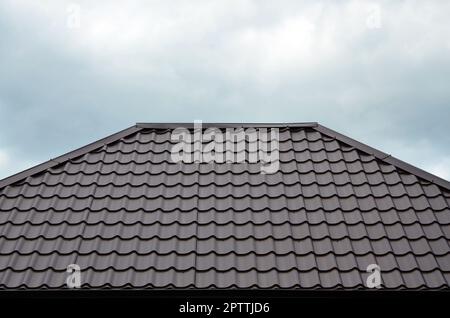 Tetto marrone piastrelle o tegole sulla casa come immagine di sfondo. Nuova sovrapposizione marrone stile classico materiale di copertura con pattern di texture su una casa vera e propria Foto Stock