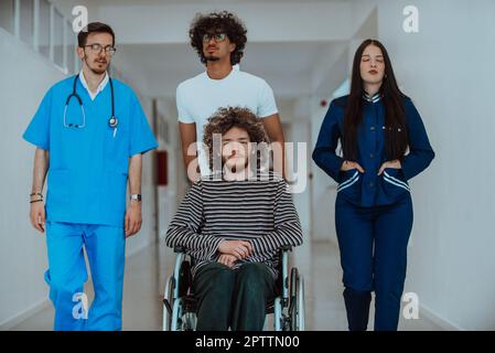 Due medici e un'infermiera camminano lungo un corridoio dell'ospedale, spingendo un paziente in una sedia a rotelle. I professionisti medici che forniscono assistenza e attenzione a. Foto Stock