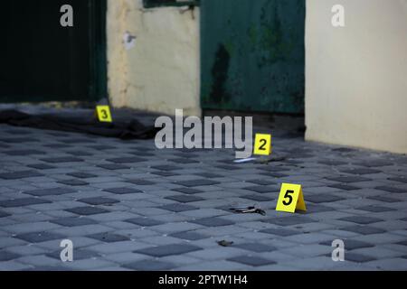 Prova con indicatore CSI giallo per la numerazione delle prove sul cortile interno in serata. Concetto del processo di indagine sulla scena del crimine Foto Stock