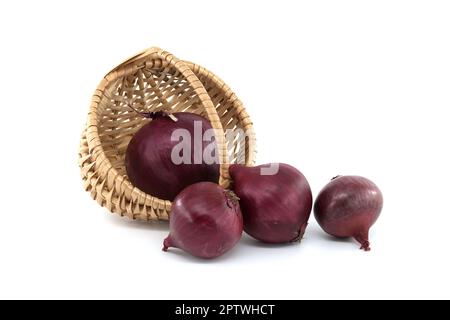 Le cipolle rosse cadono dal cestino di vimini su sfondo bianco Foto Stock