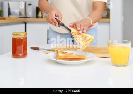 Primo piano di vista delle mani femminili mettendo pezzo di pane tostato dolce su un piatto Foto Stock