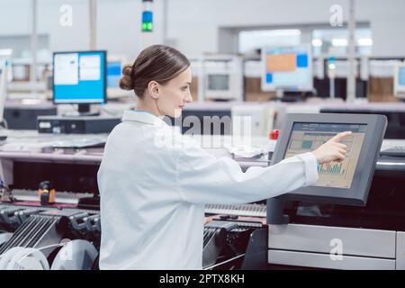 Donna in elaborazione di controllo della linea di assemblaggio in fabbrica elettronica Foto Stock