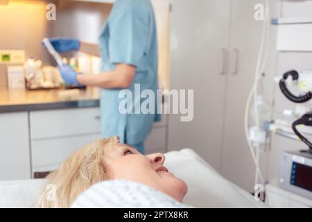 Paziente donna in ospedale che guarda infermieri che si preparano per l'intervento chirurgico Foto Stock