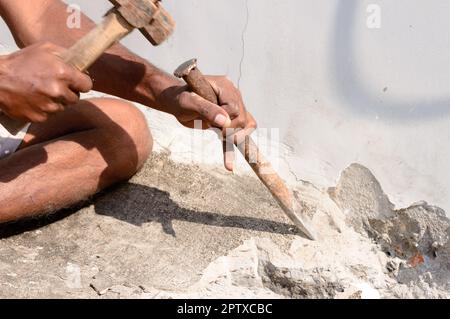 Primo piano di una parte del lavoro di costruzione che lavora con martello e scalpello in un cantiere. Foto Stock