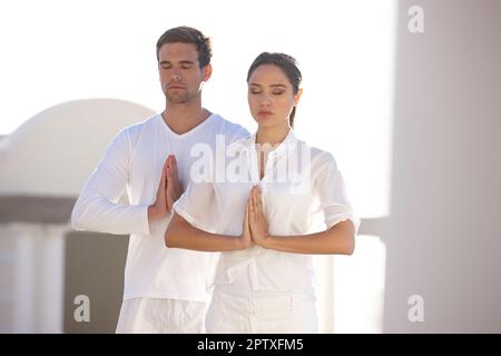 Partner mentalmente fisicamente e spiritualmente. un giovane uomo e una donna che fanno yoga all'aperto Foto Stock