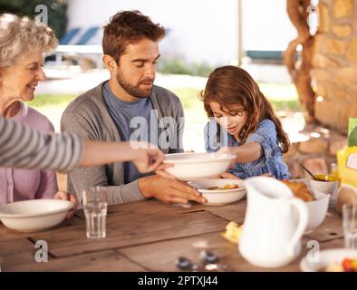 Condividere un pasto con i propri cari. una famiglia che fa colazione insieme all'esterno Foto Stock