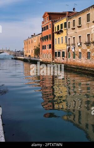 Vista su un canale con riflessi di colorati edifici tipici di Venezia Foto Stock