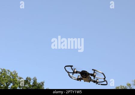 Drone con fotocamera decollare da terra e volare per prendere foto aerea al tramonto di sera parte anteriore degli alberi Foto Stock