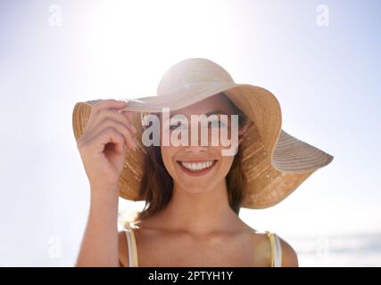 Sentendosi Summery nel suo cappello del sole. Una giovane donna che indossa un cappello alla spiaggia Foto Stock