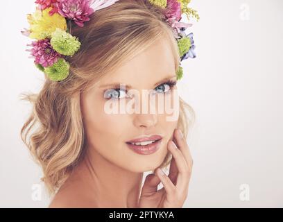 Offre una vera bellezza. Una giovane donna con un fiore arrangiato nei suoi capelli sorridendo alla macchina fotografica Foto Stock