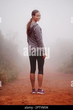 Non preoccuparti, non mi perderò nella nebbia. Una giovane donna in forma che si alza sulla spalla mentre si trova su un percorso all'aperto Foto Stock