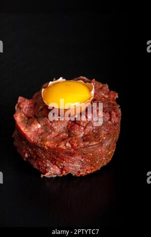 tartare di bistecca sull'ardesia nera con un uovo Foto Stock