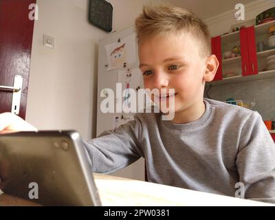 Sremska Mitrovica, Serbia, 20 maggio 2020 ragazzo biondo con laptop. Il bambino guarda il monitor. L'emozione della gioia. Foto Stock