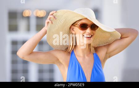 Informale stile piscina. Una donna bionda che indossa un cappello da sole e sorride alla macchina fotografica Foto Stock