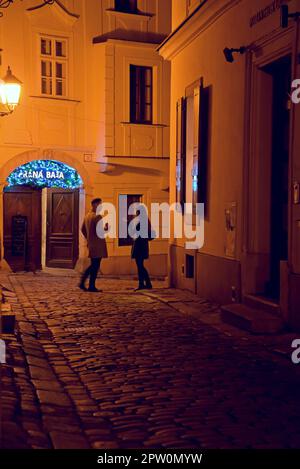 Persone in una strada acciottolata fuori da un night club nel quartiere vecchio della città di Bratislava, Slovacchia Foto Stock