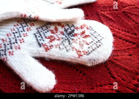 Morbidi guanti in mohair bianco lavorato a maglia con un tradizionale motivo floreale sul retro. Un paio di accessori moda Mittens. Lavorato con t rosso e nero Foto Stock