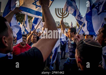 Gerusalemme, Israele. 27th Apr, 2023. I sostenitori israeliani della riforma hanno fatto sventolare le loro bandiere nazionali e ballano durante la manifestazione pro-riforma. Gli israeliani a favore della riforma giudiziaria di divisione del governo hanno partecipato a una manifestazione al di fuori della Knesset a Gerusalemme, nella più grande protesta a destra del paese in quasi due decenni. Credit: SOPA Images Limited/Alamy Live News Foto Stock