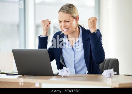Una giovane donna d'affari caucasica che urla mentre usa un computer portatile in un ufficio al lavoro. Donna che ha una giornata stressante al lavoro e mostrando la sua frustrazione. Foto Stock