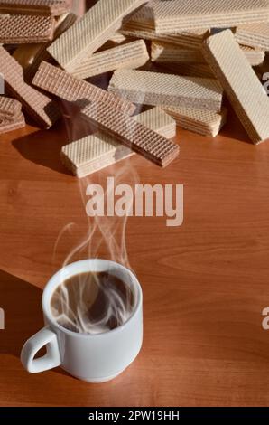 Una tazza di caffè caldo e una manciata di classico russo cialde con diversi riempimenti su un marrone la superficie di legno. Still-life di mattina festa, concetto s Foto Stock