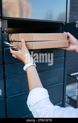 Una donna raccoglie un pacco dall'ufficio postale, ordine online, shopping online, scatola di artigianato. Concetto di vendita online Foto Stock