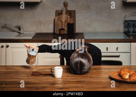 Donna addormentata che spillava caffè sul tavolo al mattino Foto Stock