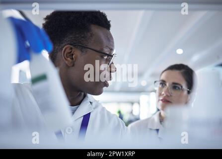 Giovane scienziato afroamericano che controlla i campioni con una collega femminile.due professionisti medici che lavorano insieme sugli esperimenti nel laboratorio. Focuse Foto Stock