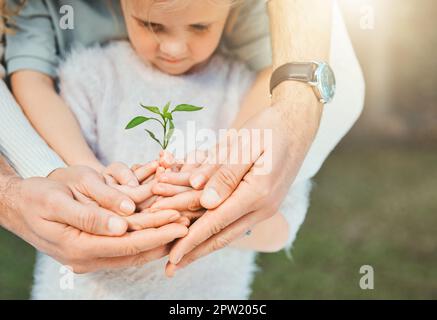 L'amore per la famiglia non si rompe mai. una famiglia irriconoscibile che tiene piante che crescono dal suolo Foto Stock