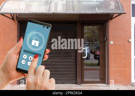 Immagine ritagliata della femmina che immette codice chiave segreto per ottenere l'accesso e passare edificio utilizzando l'applicazione sul telefono cellulare, donna premendo i pulsanti su Foto Stock