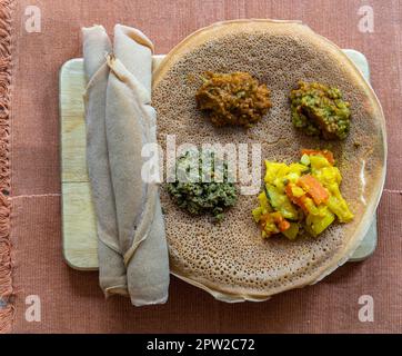 Injera con lenticchie e verdure, pane piatto acro fermentato simile a una frittella, un alimento base dell'Etiopia e dell'Eritrea Foto Stock